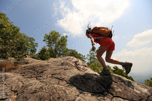 young asian woman hiker climbing rock on mountain peak cliff © lzf