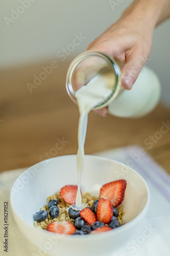 Granola for breakfast / Men is preparing granola with fruits and milk