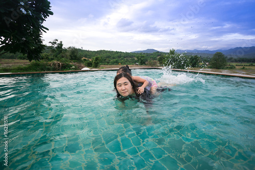 Mother and daughter relaxing in a waterpool outdoors on Thailand mountain 