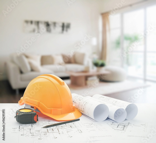 architectural blueprint with safety helmet and tools over modern living room interior
