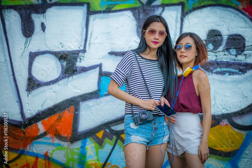tourism, travel, leisure, holidays and friendship concept - smiling teenage girls with camera outdoors,And fashion sunglasses.