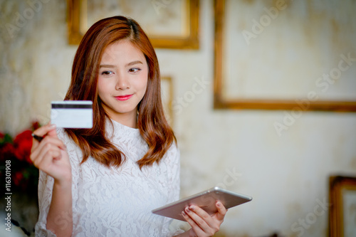 Happy woman shopping online, holding credit card, using tablet c