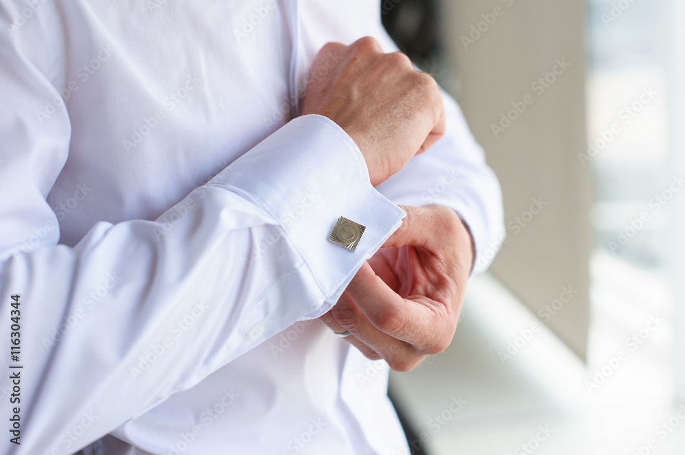 Male buttons cufflinks. Businessman buttons cufflinks in white shirt. Groom in morning wears shirt to a wedding. Male buttons cufflinks. Businessman buttons cufflinks in white shirt. Groom in morning wears shirt to a wedding.