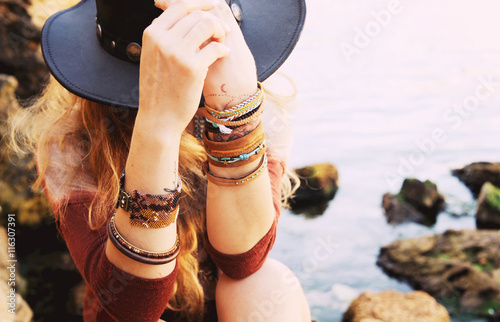 Fotografia Female hands with boho chic bracelets holding black hat