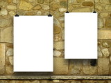Close-up detail of two blank frames hanged by clips against weathered stone wall background