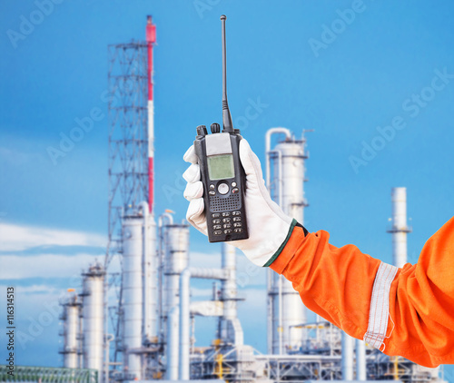 walkie-talkie radio in hand distillation background. comunication in refinery process