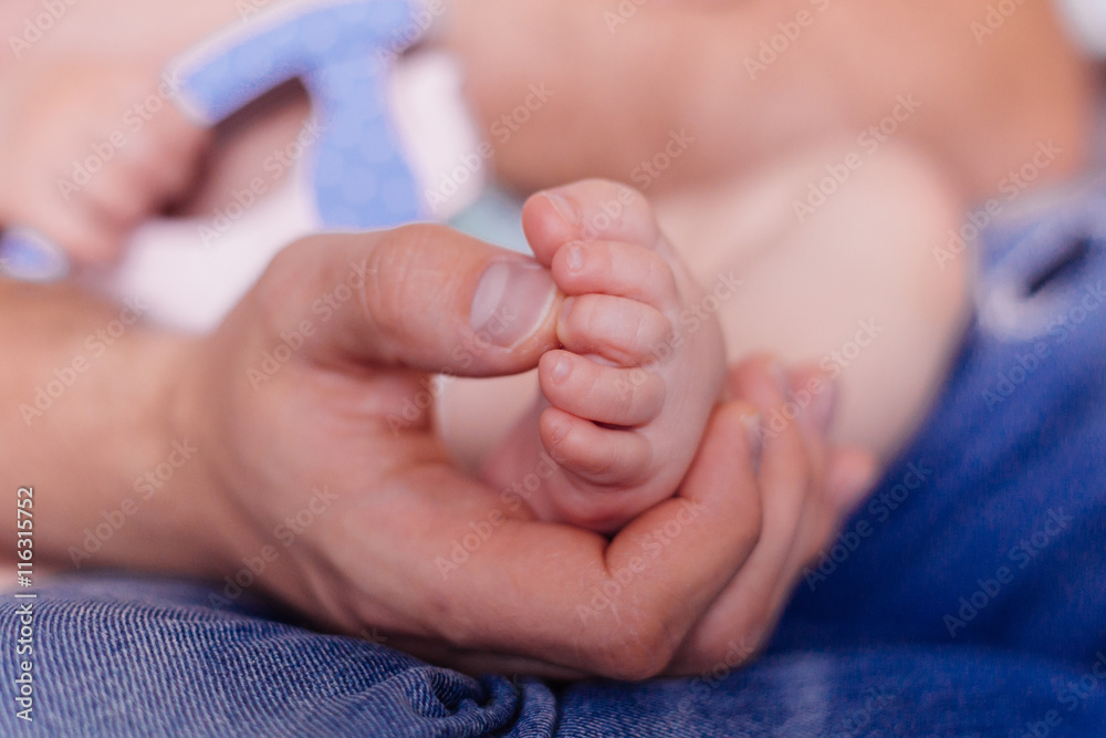 Man hold small baby leg in hand