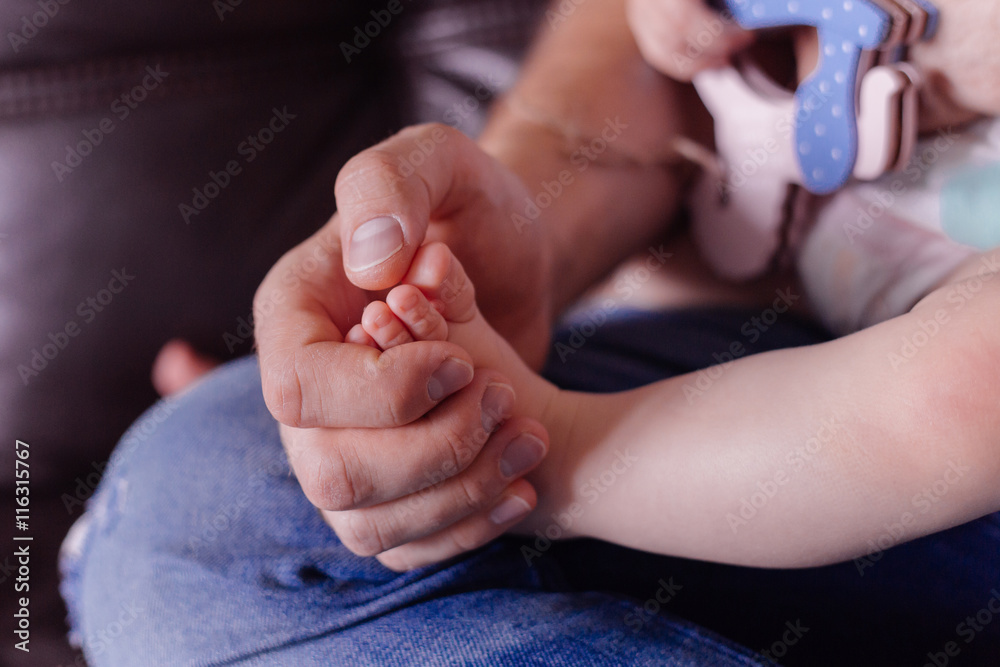 Man hold small baby leg in hand