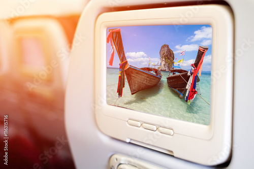 Aircraft monitor in front of passenger seat showing Thai boats a photo