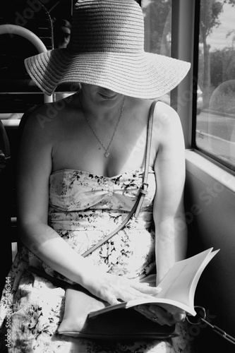 Woman reading a book on train bus in b/w format photo