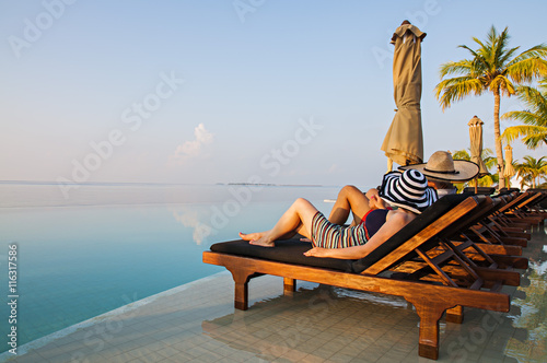 Young Couple Resting on Sun Loungers by swimming Pool