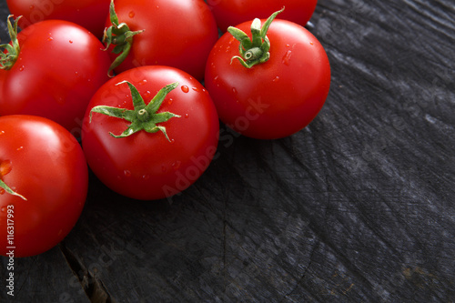 Red cherry tomatoes on black rustic wood background