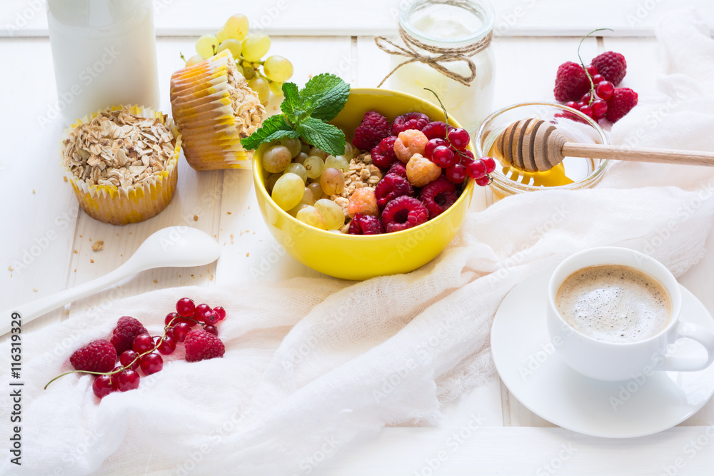 Healthy breakfast: muesli, honey, yogurt, muffins, coffee and fresh berries on white wooden background Healthy breakfast: muesli, honey, yogurt, muffins, coffee and fresh berries on white wooden background