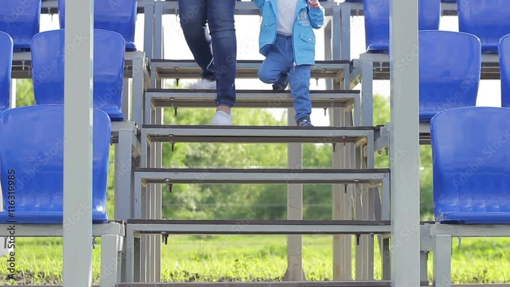 Little boy and his mother down the stairs of the stadium Little boy and his mother down the stairs of the stadium