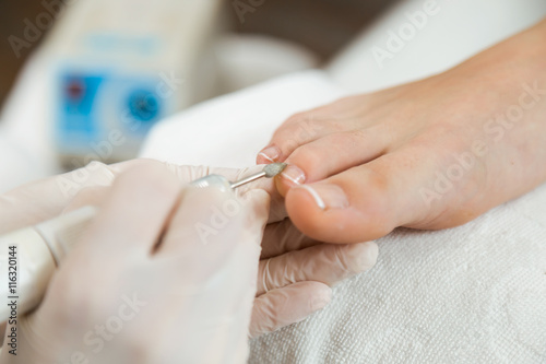 Young woman doing pedicure in salon. Beauty concept.