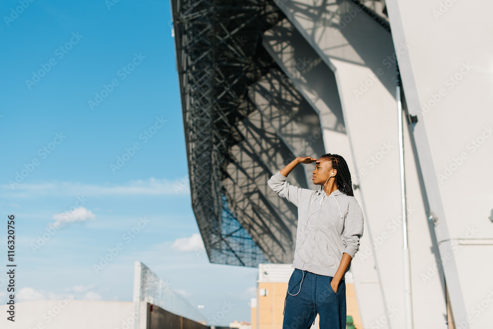 Beautiful african american woman looking ahead with the hand in forehead,modern building on background