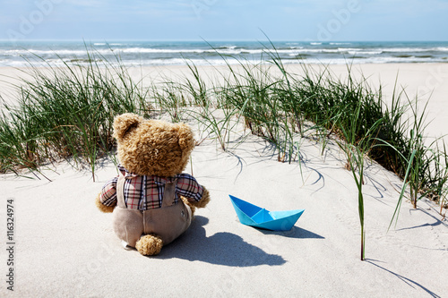 Teddy und Papierschiff am Strand photo