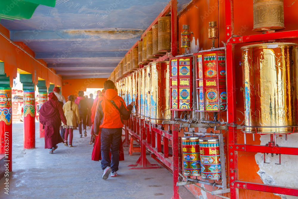 Buddhist nun walking touch a prayer wheels around the sanctuary at Larung gar (Buddhist Academy) in Sichuan, China. This is the public place
