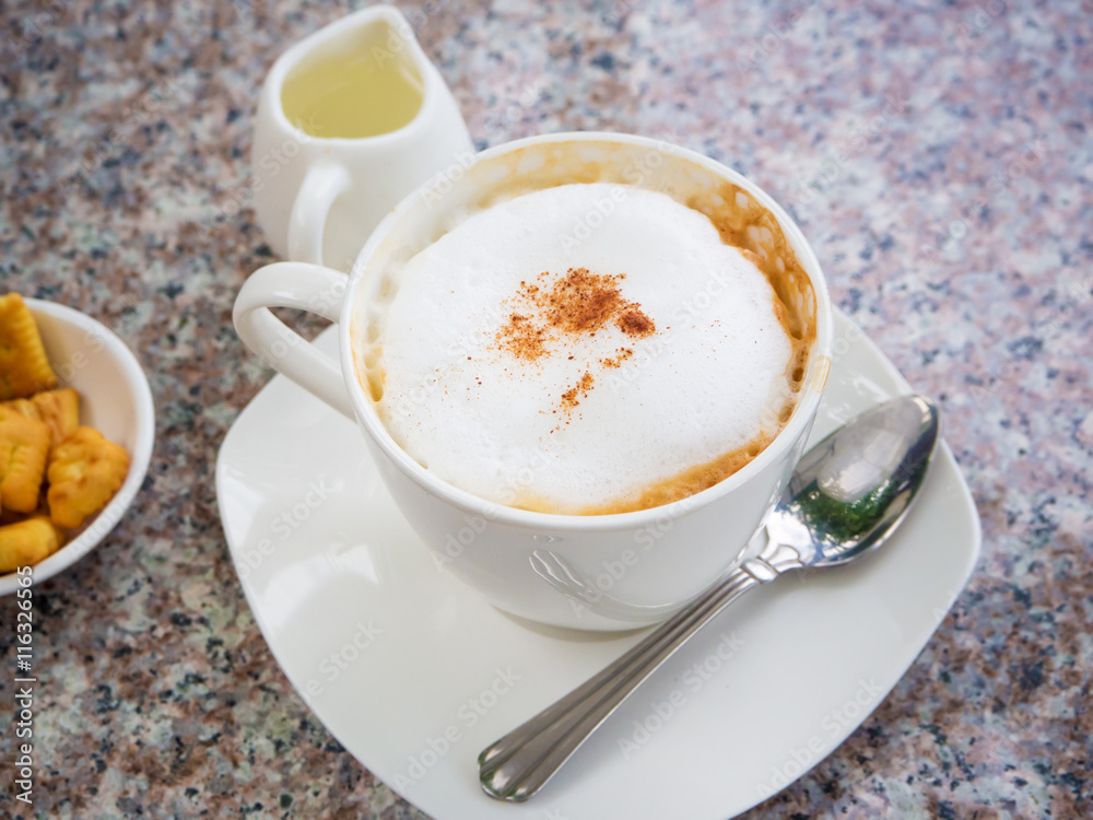 White cup of cappuccino stands on the rock table, selective focus White cup of cappuccino stands on the rock table, selective focus