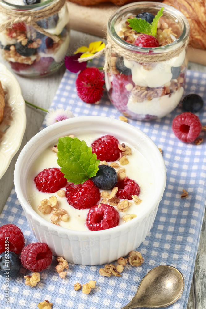 Breakfast table: bowl of yogurt with muesli and fresh fruits Breakfast table: bowl of yogurt with muesli and fresh fruits