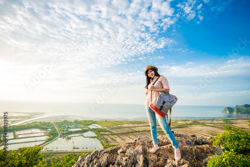 Young woman with backpack standing on a peak of cliff and enjoyi photo