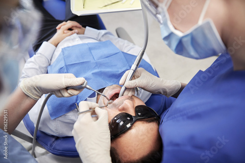 female dentist treating male patient teeth