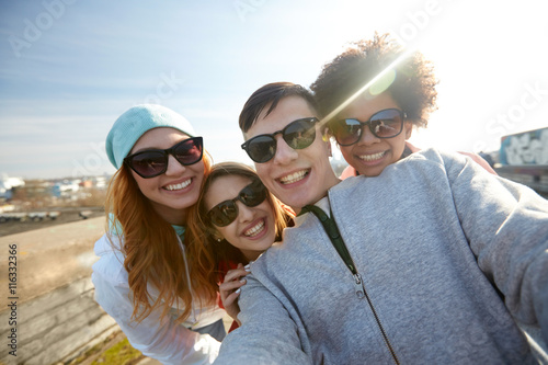 group of happy friends taking selfie on street