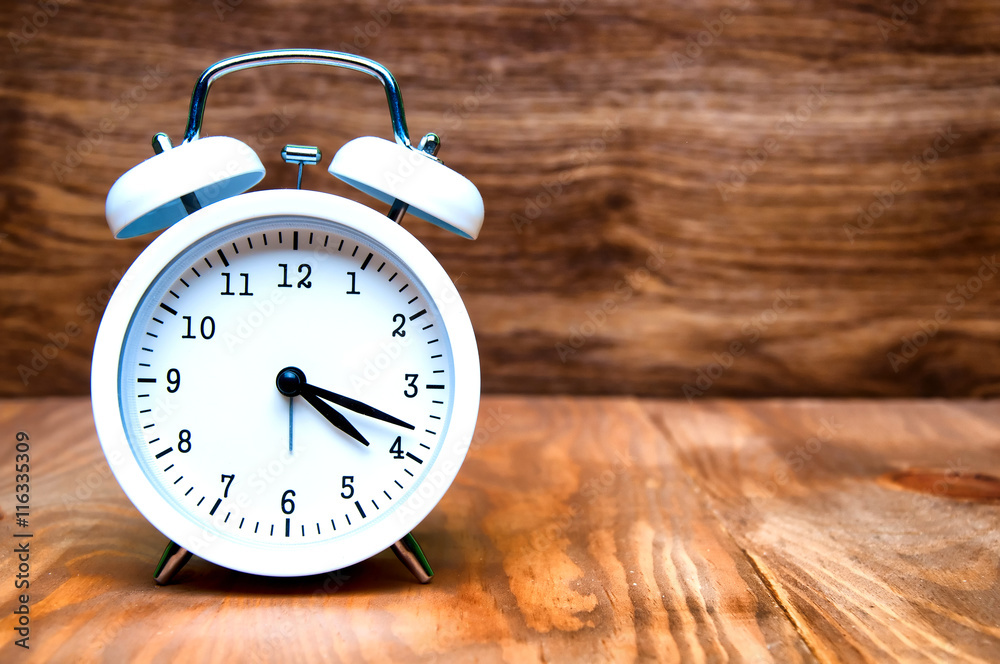 White alarm clock isolated on wooden background White alarm clock isolated on wooden background