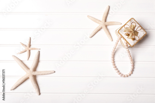 Summer concept: Idea with starfish and pearl necklace on white wooden with space for text.