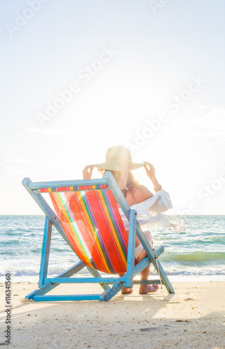 Fototapeta Naklejka Na Ścianę i Meble -  Young woman in hat sitting on beach
