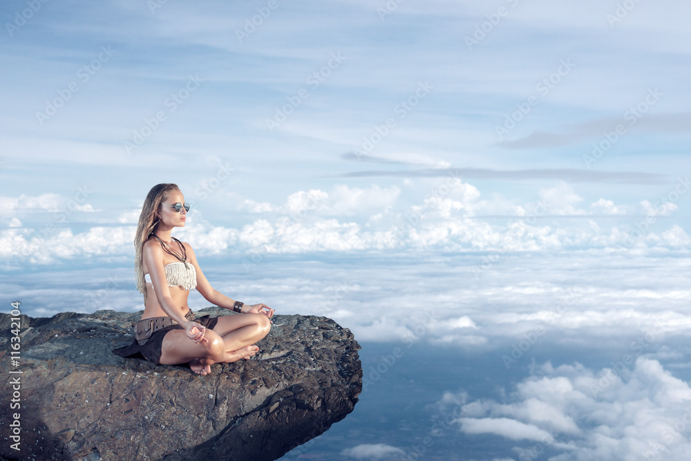 Woman meditating on a cliff