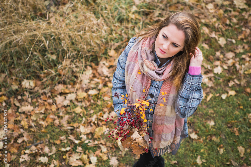 Girl walking in autumn park. Bouquet of leaves and berries. Girl dressed in a coat and scarf. Girl walking in autumn park. Bouquet of leaves and berries. Girl dressed in a coat and scarf.