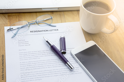 Businessman review his resignation letter on his desk before sending to his boss to quit his job with laptop computer and a cup of coffee.