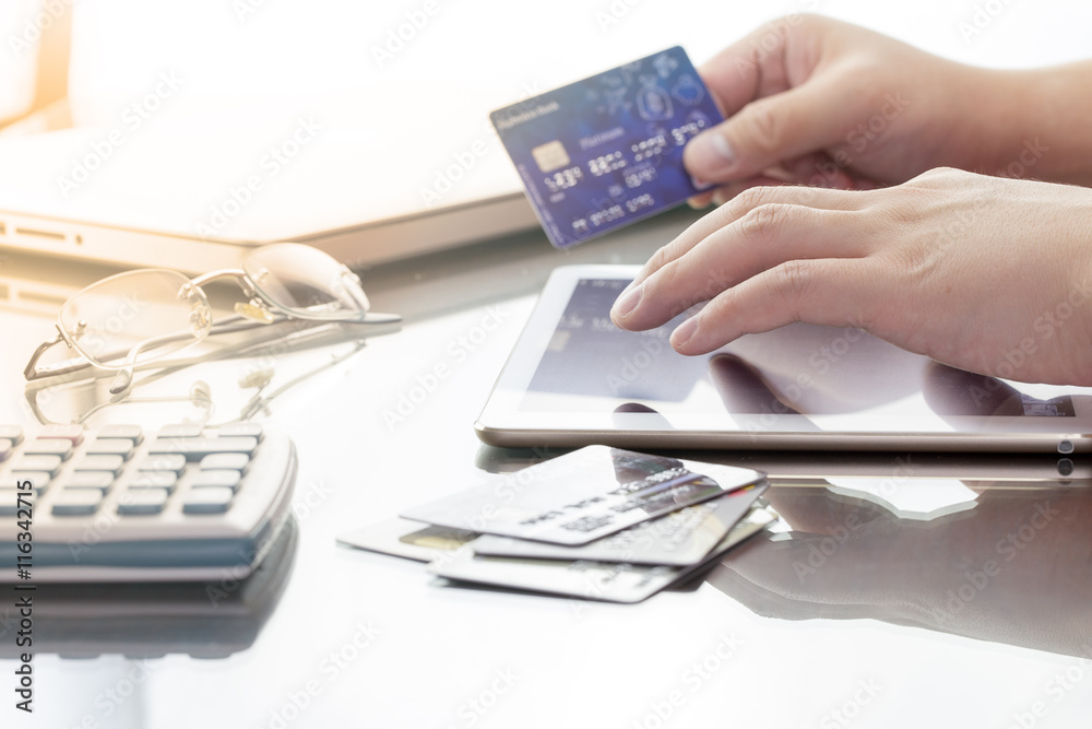 Man using his digital tablet while holding a credit card intent to online shopping, concept with digital business or e-commerce concept. close up, warm tone. Man using his digital tablet while holding a credit card intent to online shopping, concept with digital business or e-commerce concept. close up, warm tone.