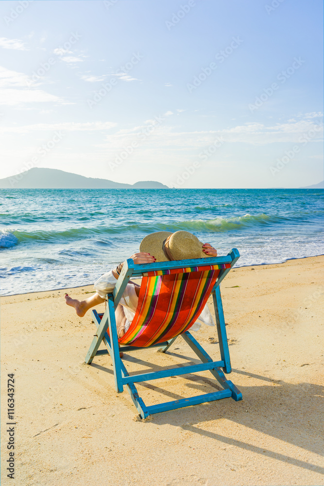 Young woman in hat sitting on beach