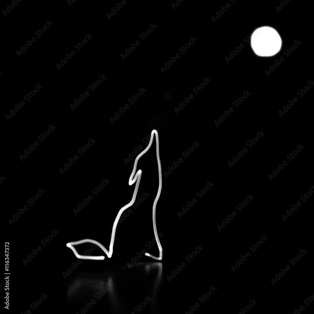 Naklejka premium Drawn with light wolf howling at the moon illustration on black