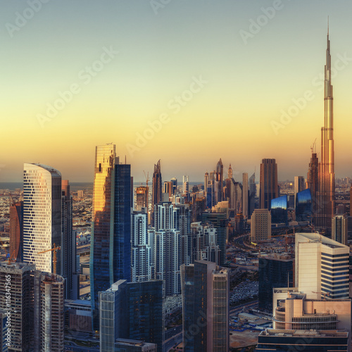 Big modern city with futuristic architectrure at sunset. Beautiful aerial cityscape with skyscrapers. Dubai, UAE. Travel background.