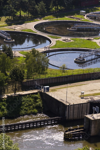 Men checking water storage tanks at sewage treatment plant