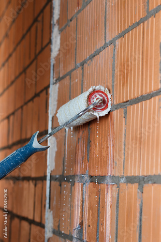 primer on the brick wall with a roller