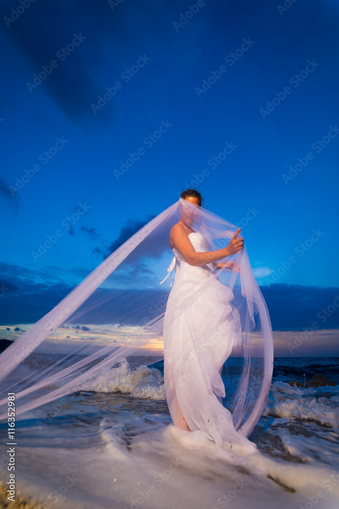 Naklejka premium bride on a tropical beach at sunset