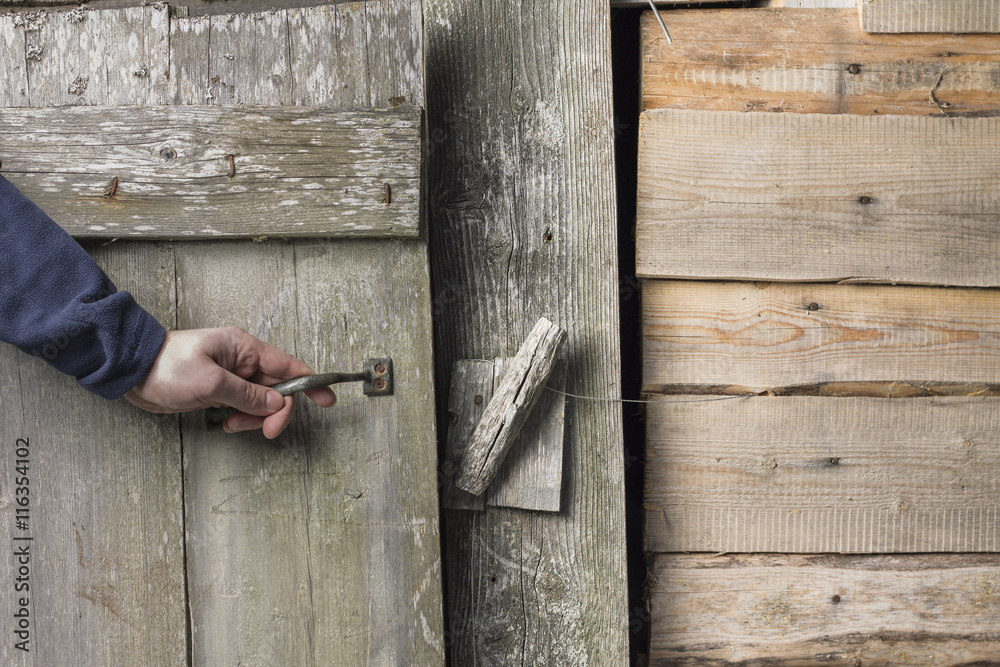 a person opens an old wooden door with a latch a person opens an old wooden door with a latch