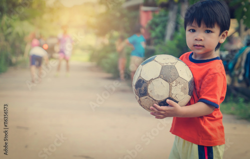 Poor Asian Boy playing with old rustic soccer ball