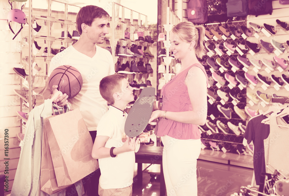 man and woman buying skateboard for son in sport shop