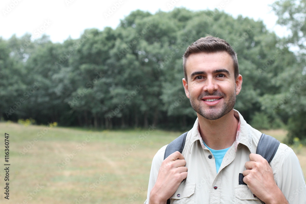 Fototapeta premium Young man hiking smiling happy portrait. Male hiker walking in forest.