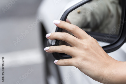 girl with beautiful manicure in car regulates  rear view mirror