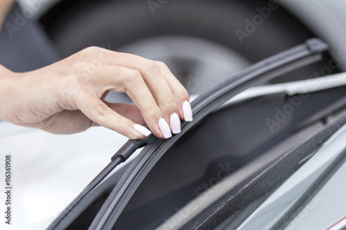 Girls hand corrects wipers on the glass of the car. 