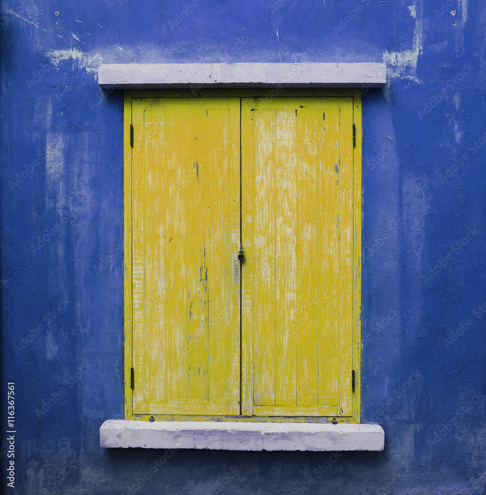 Yellow wooden window an blue wall
