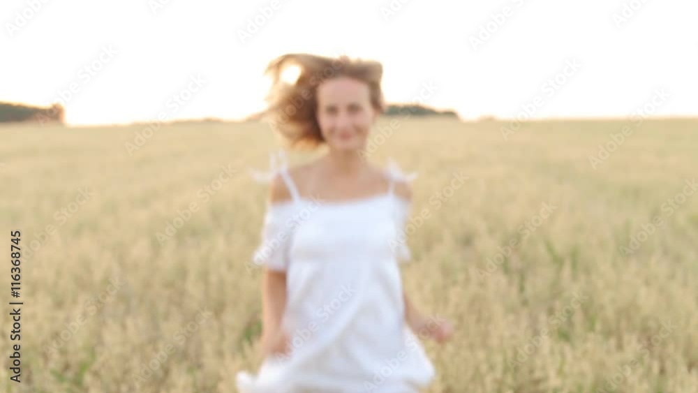 Happy, young woman with a toothy smile running across the wheat field Happy, young woman with a toothy smile running across the wheat field