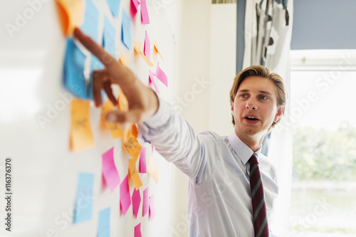 Young businessman explaining strategy in adhesive notes at office