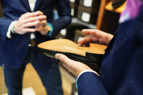 Cropped image of salesman holding shoe while standing with customer in store
